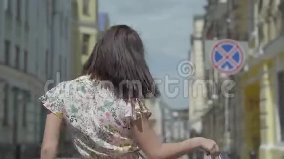 无忧无虑的年轻女子手里拿着购物袋在欧洲老城区走来走去跳舞转悠视频的预览图