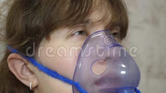 一个戴口罩的生病女孩吸入一个喷雾瓶戴蓝色医院面具的女人吸入呼吸道的蒸气视频的预览图