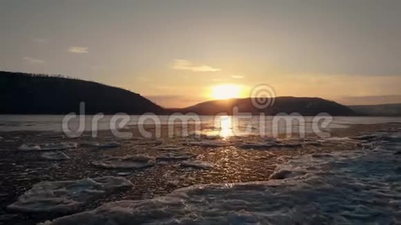 这一个鸟瞰图日落于山河流或湖泊上覆盖着人在岸边结冰低视频的预览图