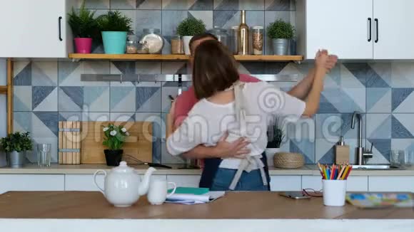 幸福的一对新婚夫妇在家厨房里跳舞听音乐爱玩视频的预览图