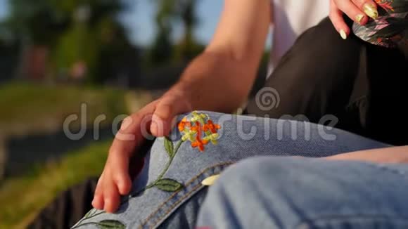那个人把手放在女孩膝盖上然后抚摸它浪漫的夫妇喝咖啡坐在绿草上关闭视频的预览图