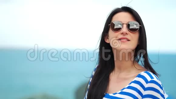 中等特写时尚的旅游女性戴太阳镜在海天自然背景视频的预览图