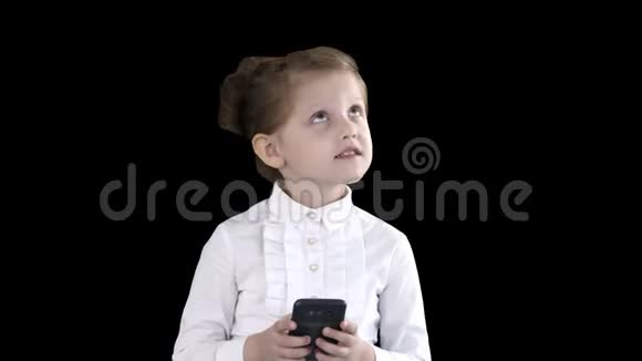 可爱的小女孩看着智能手机写着一条信息阿尔法频道视频的预览图