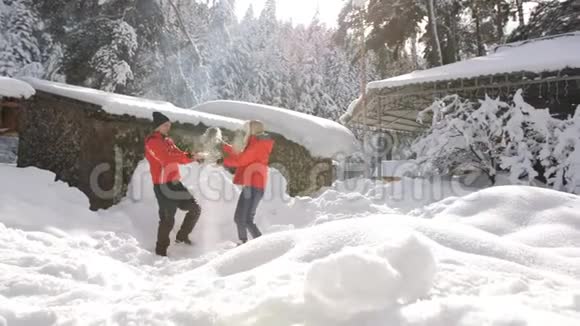 一对夫妇在后院的冬山小屋里在朝阳下闲逛这对夫妇把雪扔进了天空视频的预览图