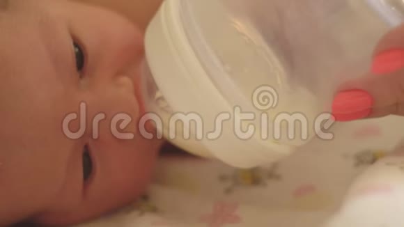 母亲用婴儿配方奶粉特写镜头用奶瓶喂小白种人女孩视频的预览图