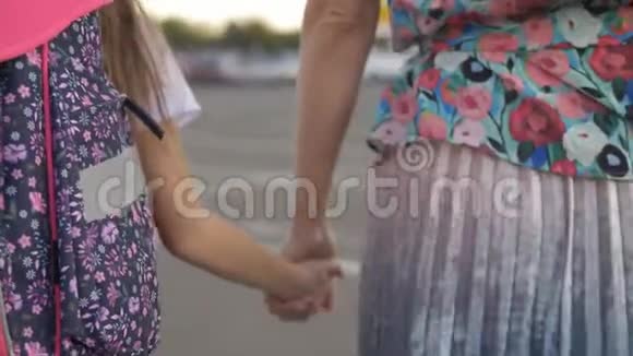妈妈带着女儿上学的女孩背着背包走在公园里后景视频的预览图