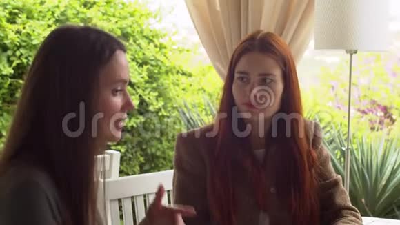 两个女朋友在咖啡馆里讨论她们男朋友的生活一边喝茶慢动作视频的预览图