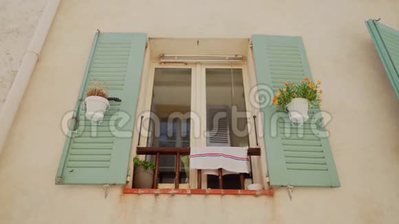 美丽的窗户开着绿色的百叶窗和花挂在地中海住宅米色墙上的花盆里视频的预览图