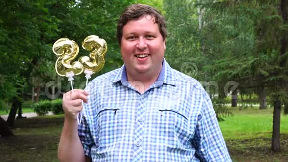 大个子拿着金色的气球把23号放在户外23周年庆祝晚会视频的预览图
