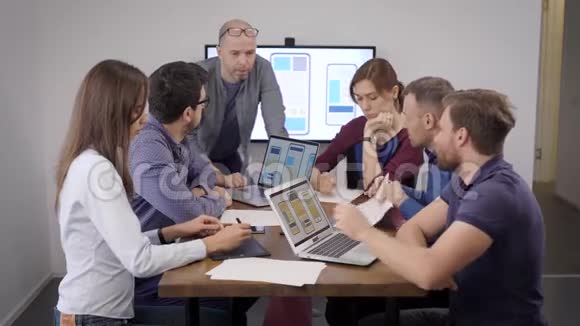 创意生意由开发人员和设计师组成的团队讨论移动应用程序的布局男女视频的预览图