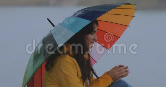 女人坐在伞下享受秋雨喝茶视频的预览图