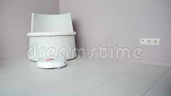 圆形机器人吸尘器整理公寓白色吸尘器自动在椅子周围驾驶清洁地板视频的预览图