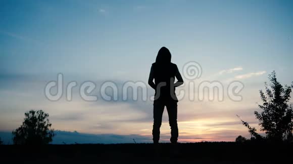日落时分一个戴着兜帽的人独自站在一片美丽的天空中视频的预览图