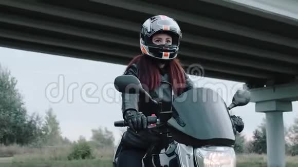 一个骑摩托车的女孩向前看特写镜头背景中是一座桥镜头绕着女孩转4K视频的预览图