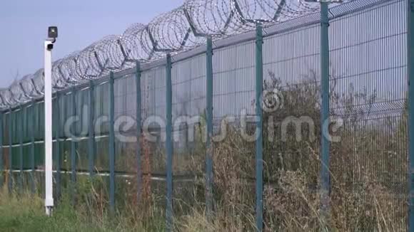 监狱围栏上面有铁丝网和种植植物视频的预览图