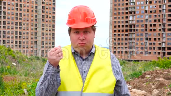有钱的概念建筑工人在施工现场背景上用手指摩擦现金标志视频的预览图