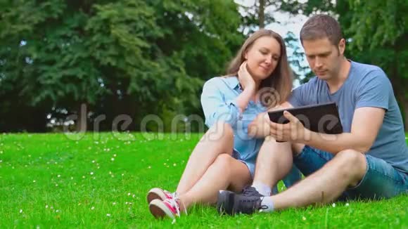 男人和女人在公园里用平板电脑视频的预览图