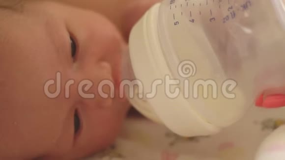 母亲用婴儿配方奶粉特写镜头用奶瓶喂小白种人女孩视频的预览图