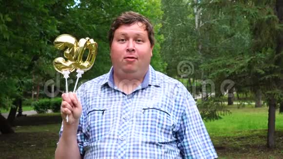 大个子拿着金色气球把30号放在户外30周年庆祝晚会视频的预览图