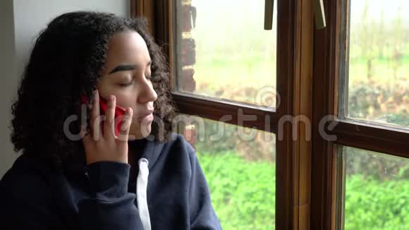 悲伤沮丧不快乐的混血非裔美国少女少女坐在窗边打电话对她说话视频的预览图