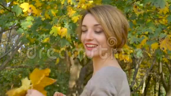 一位有着迷人情感的年轻女子她留着一头金发穿着一件紧身连衣裙上面挂着一束秋叶视频的预览图