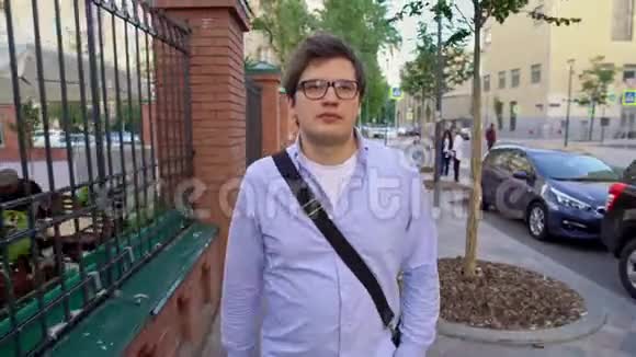 中锋戴着眼镜穿着蓝色衬衫在街上行走视频的预览图