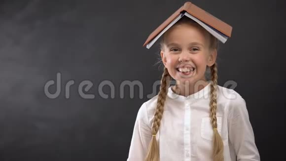 令人兴奋的女学生头上戴着书对着镜头微笑教育理念视频的预览图