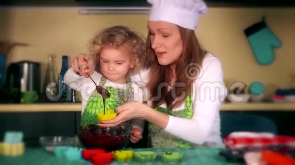 快乐的母女在厨房准备纸杯蛋糕戏剧性的颜色分级视频的预览图