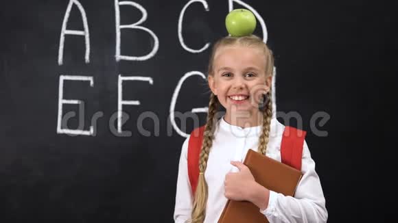 漂亮的女学生站在黑板旁边头上戴着苹果这是个绝妙的主意视频的预览图