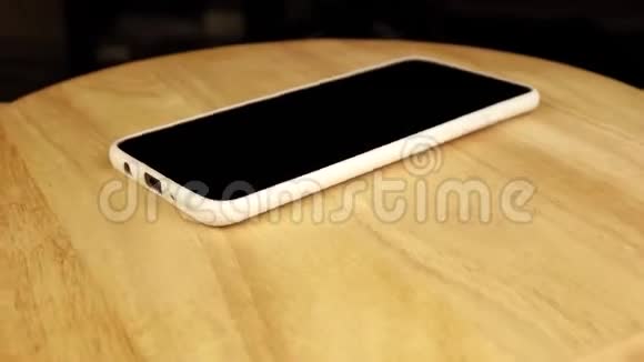 黑色手机白色外壳在木架上旋转360度视频的预览图