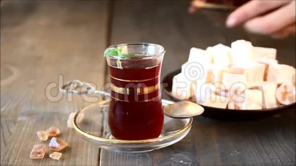 女人手把土茶放在传统的玻璃杯里的木桌上东方人视频的预览图