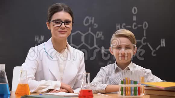 年轻的女化学老师和男生看着镜头微笑着上课视频的预览图