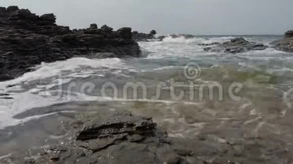 汹涌的大海在岩石湾的岩石上撞击着干净的海水视频的预览图
