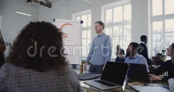年轻微笑快乐的欧洲商人带领多民族企业员工参加办公室团队销售培训研讨会视频的预览图