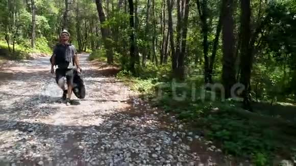一个在森林小径上旅游的年轻人拿着背包在松林里旅行2019年8月视频的预览图