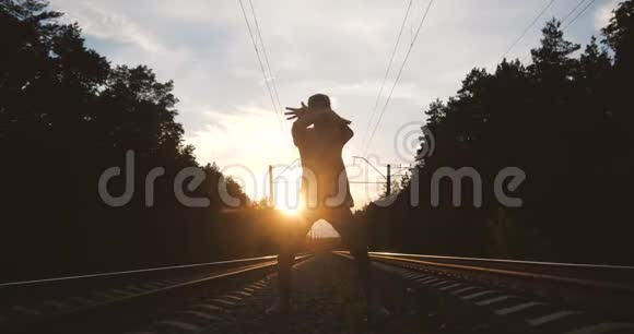 4k日落时分深色头发的男人在铁轨附近跳舞动作缓慢视频的预览图