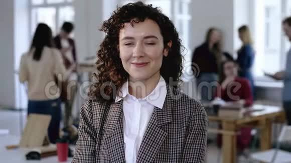快乐的欧洲年轻商务女性身着优雅的正式套装卷发在现代办公室摆姿势笑容灿烂视频的预览图
