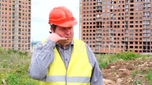 男性建筑工头工人或建筑师在建筑工地上显示呼叫我的手势视频的预览图