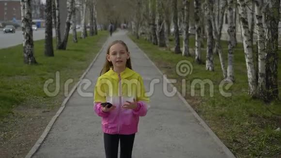 女孩走在街上手里拿着智能手机拿着相机说话视频的预览图