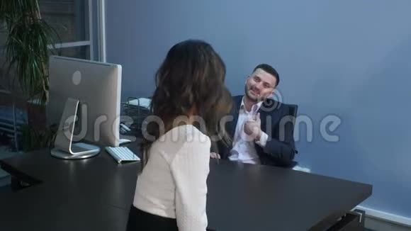 一个微笑的商人在办公室的非正式会议上和他的同事交谈视频的预览图
