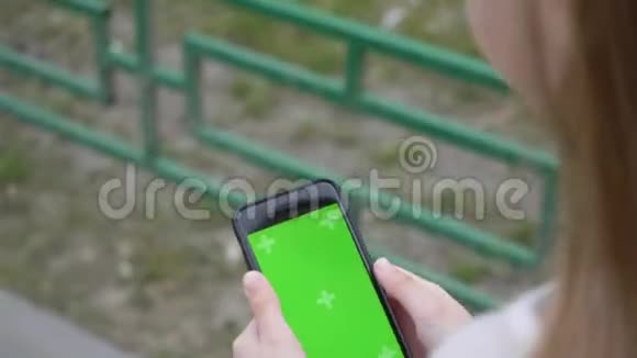 女手刷触摸屏手机户外手年轻女子滑动智能手机屏幕上的城市街道双手视频的预览图