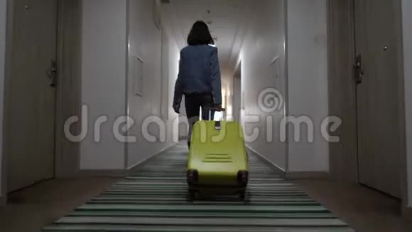 一个年轻的女孩带着一个手提箱沿着酒店走廊走入住酒店从后面看4k决议视频的预览图