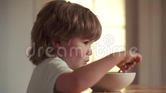 快乐的婴儿用勺子吃食物美丽的孩子在家吃早餐的肖像养育子女视频的预览图