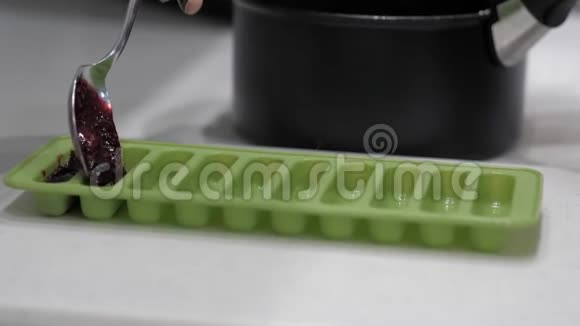 女用手用金属勺子将浆果酱放入绿色硅胶模具中特写视频的预览图