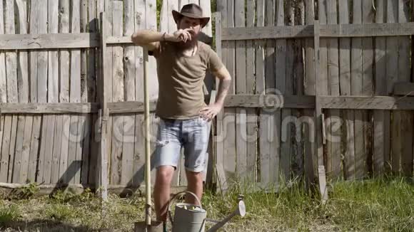 一幅长胡子的农夫的全身画像他拿着铲子在一个木制操场上的农场里玩得很开心生态农场希普斯特农民视频的预览图