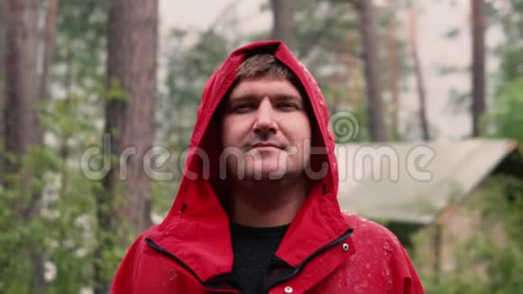 一个穿着红色夹克衫的人站在森林里的雨中视频的预览图