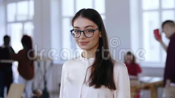 令人惊叹的肖像自信的千禧年黑发商业女经理眼镜摆在工作现代办公室视频的预览图