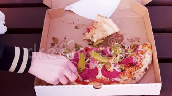 快关门披萨盒在长凳上女人的手拿着胡椒和披萨从他手里滴着果汁视频的预览图