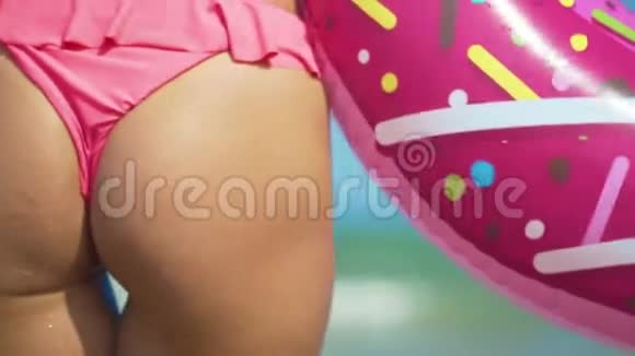 年轻的女人臀部走在大海与粉红色充气甜甜圈视频的预览图
