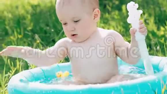一个夏天小男孩正在游泳玩着在充气游泳池里溅起的水花视频的预览图